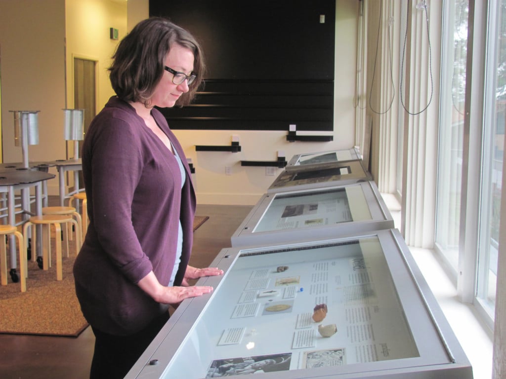 Meagan Huff, museum technician, inspects one of four themed cases at the newly revamped visitor center.