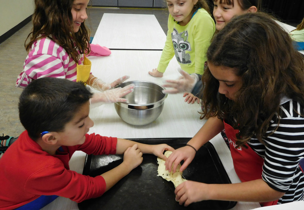Evan Schuett and his sister, Helena, roll out dough for making sausage crescent cheese balls while Sophia Schuett (left), Kierra Thompson and Jasmine Bergstrom look on.    