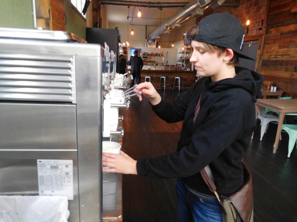 Heidi Armstrong, 22, of Washougal, prepares a cup of salted caramel and cake batter Dannon YoCream frozen yogurt, with assorted toppings, at Smiley's Yogurt and Deli, in downtown Washougal. The new eatery, owned by Paul Le, also offers sandwiches, soups and salads. 