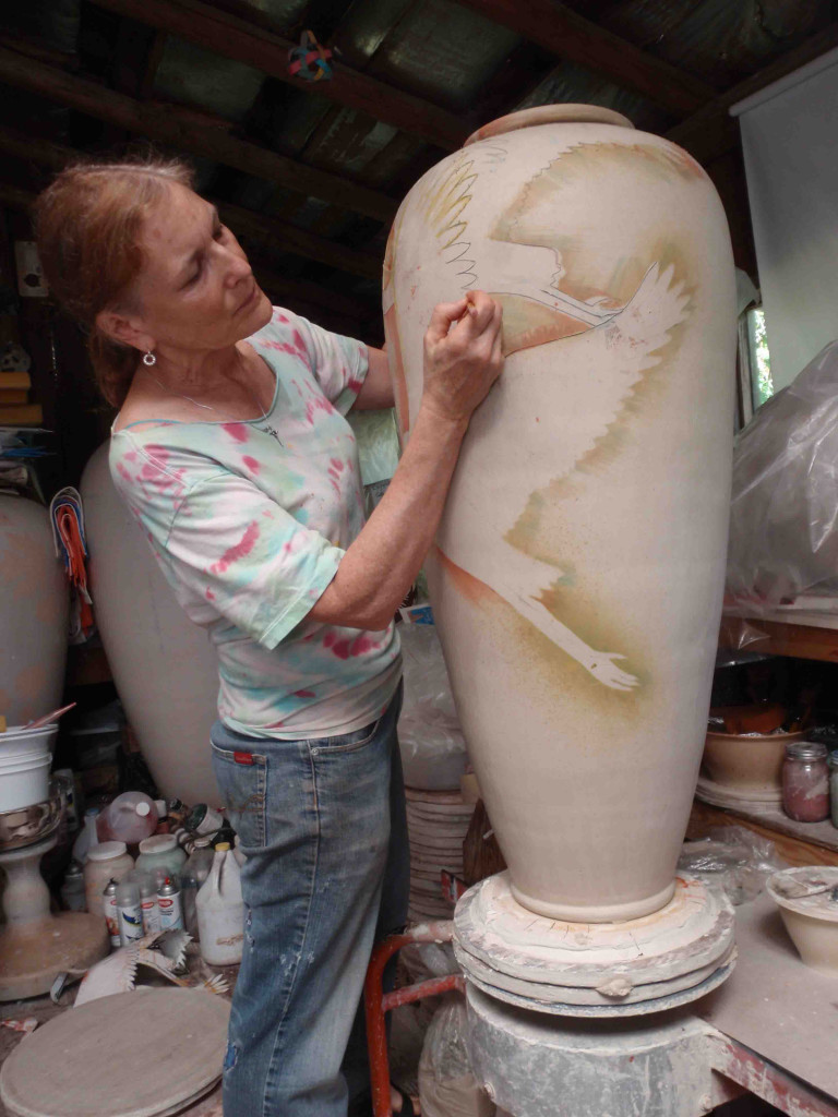 Boni Deal draws an image of a heron onto one of her and husband Dave Deal's urn pieces. Their work will be on exhibit as part of a show at the Second Story Gallery at the Camas library. An opening reception will be held Friday, from 5 to 8 p.m. (Contributed photo)