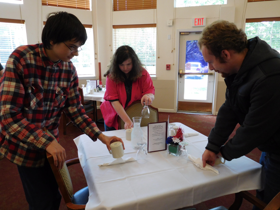 Pathways students, from left, Nova Delp, Beverly Carlson and Michael Neketuk prepare a table for lunch service at Columbia Ridge Senior Living. 