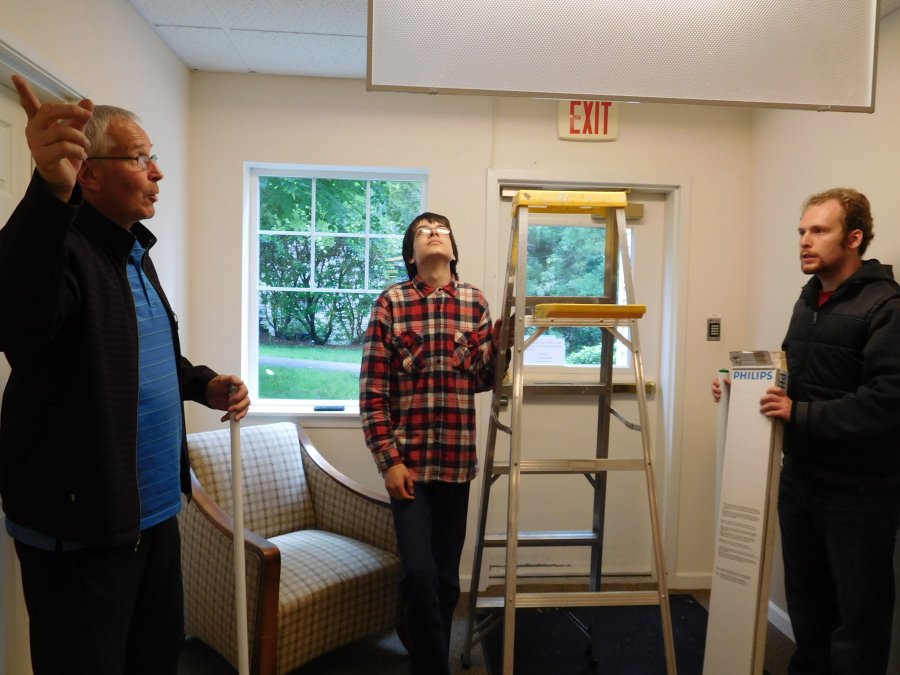 Teacher Eric Balholm discusses options on repairing a light fixture at Columbia Ridge Senior Living with Delp, left, and Neketuk.