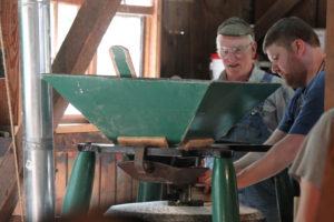 Fred Schulz, of La Center, (left) and Ian Frew, of Vancouver, (right) operate the Buhr mill, then provide samples of the flour to visitors. They are two of 15 volunteers who regularly help out when the Cedar Creek Grist Mill is open to the public on weekends. 
