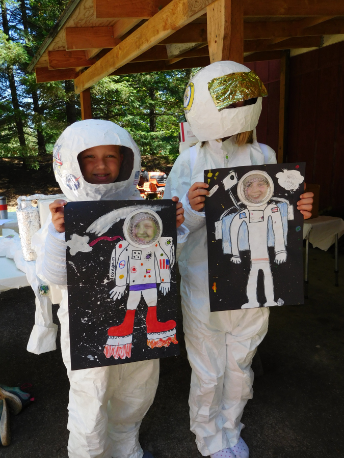 Savannah Roblin, left, and Erin Connelly proudly display their astronaut self portraits, paper mache helmets and backpacks. The space suits were created from Tyvek paint suits, and the arms are made out of dryer vents.