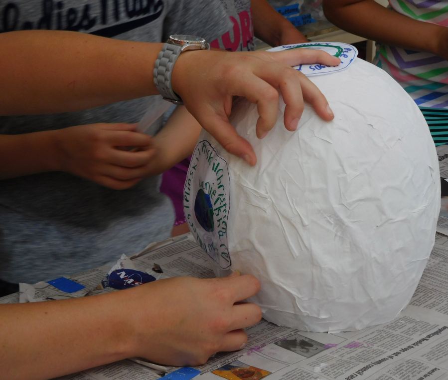 Participants put the finishing touches on their paper mache astronaut helmets.