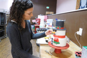 Nikki O'Keeffe began experimenting with handcrafted cakes after her children were born. Her creations can take up to 15 hours to complete. Here, O'Keeffe puts the finishing touches on a snowman cake. (Contributed photo)