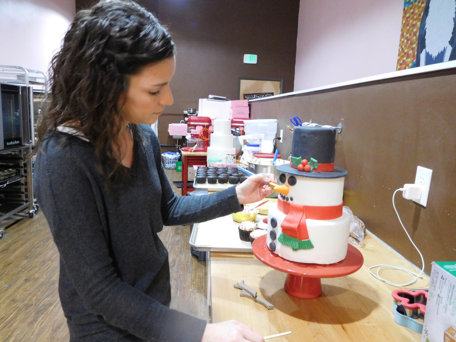 Nikki O'Keeffe began experimenting with handcrafted cakes after her children were born. Her creations can take up to 15 hours to complete. Here, O'Keeffe puts the finishing touches on a snowman cake. (Contributed photo)