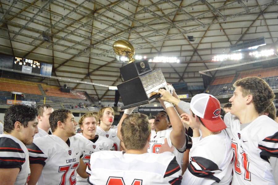 Surrounded by his best friends, Marcus Gray holds up the golden football trophy after Camas beat Richland 24-14 to become state champions for the first time in school history Saturday, in Tacoma. 