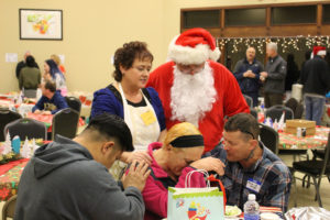 Volunteers Rueben Muniz, Julia Watts, Robert Hollibaugh  and Rick Haag take a moment to pray with one of the attendees at the Refuel Washougal Christmas dinner Sunday. Free meals were served to more than 150 people at the Washougal Community Center. (Photo courtesy of Christina Johnson)