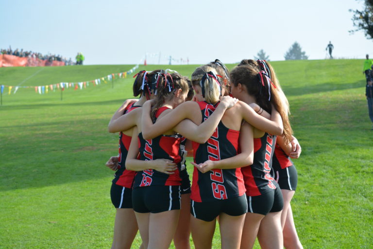 The Camas High School girls cross country runners huddle up before their state championship race on the Sun Willows Golf Course in Pasco.