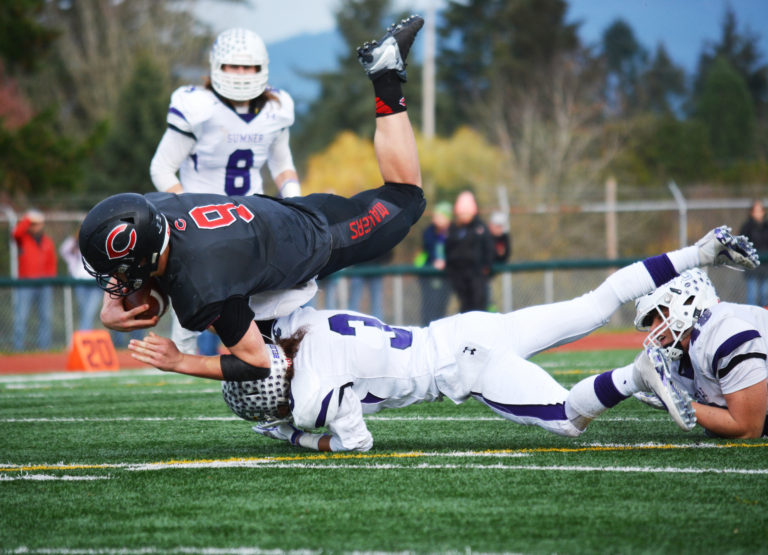 Camas quarterback Jack Colletto jumps over the defender to gain more yards.