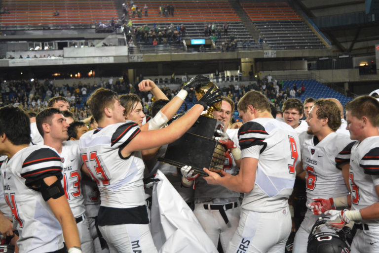 The Camas football players grab hold of the golden football.