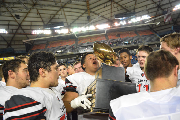 Marcus Gray and teammates he considers brothers admire the 4A state football championship trophy they just won at the Tacoma Dome.