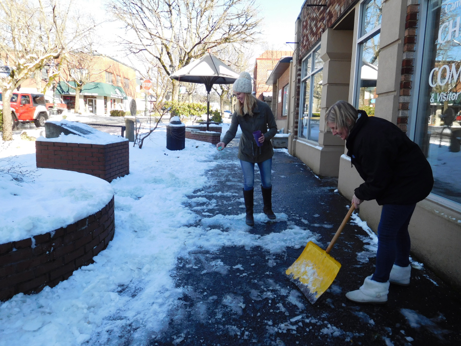 Amy Begley, owner of Forever Growing Kids in downtown Camas (front), and her landlord, Kate Rood, shovel and rock salt the sidewalks outside her store, and others, last week.