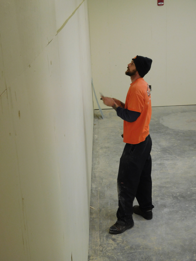 A worker prepares the walls for painting at the transportation facility.