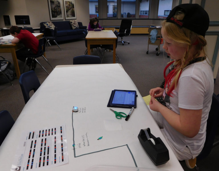 A student in the coding club uses the &quot;blocky&quot; code language on an iPad to help create commands for her Ozobot.