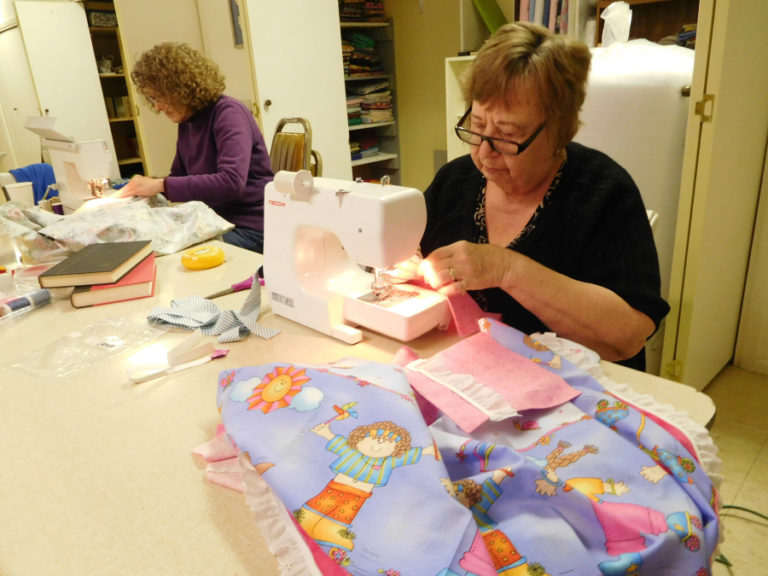 Linda Christensen (left) and Sherry Spiekerman (right) sew pockets onto dresses for Hope 4 Women International&#039;s &quot;Dress a Girl Around the World&quot; program.