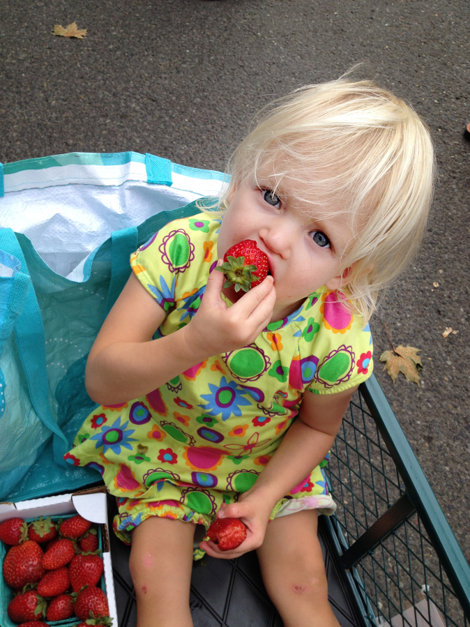 A child enjoys a fresh, regionally grown strawberry at the Camas Farmer’s Market.  Opening day of the market’s 2017 season is Wednesday, June 7, and will feature a health fair with local practitioners.