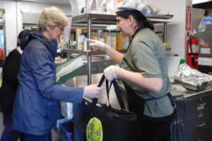 Meals on Wheels volunteer driver Marianne Reiter (left) does a final check before taking her delivery items from chef Valentina Diriyenko at the Washougal Meals on Wheels site Thursday, May 11.