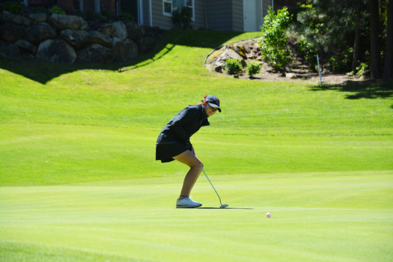 Hailey Oster teeters on the brink watching her golf ball drop into the cup on the 16th green May 26, on the MeadowWood course in Spokane.