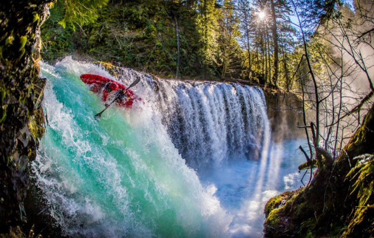 A kayaker sails over a waterfall.