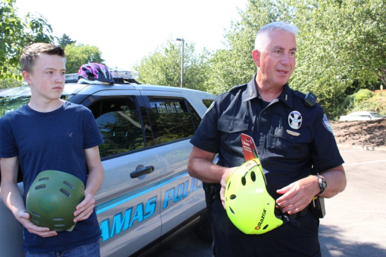 Camas Police Chief Mitch Lackey (right) discusses his department&#039;s third annual free bike helmet program, while 14-year-old Hayden Stinchfield, who recently suffered injuries during a bicycling accident, looks on.