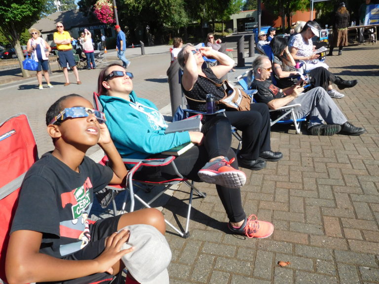 More than 100 area residents attended the City of Washougal’s eclipse viewing event, in Reflection Plaza Monday morning. They were entertained by pre-recorded music featuring sun and moon themes. (Photo by Dawn Feldhaus/Post-Record)
