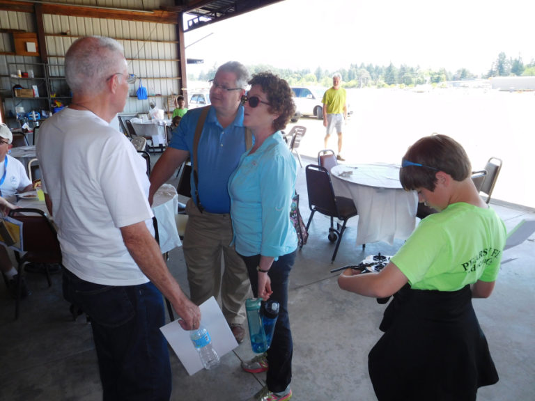 Camas-Washougal Aviation Association President Kent Mehrer (left) speaks to the parents of an aviation camp participant after a lunch and graduation ceremony held July 15 at Grove Field Airport near Camas.