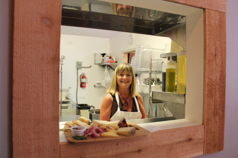 Raechill Dotson, one of four owners of the new Salud! wine bar, events center and wine storage facility in downtown Camas, delivers a plate of food to a server through the Salud! kitchen window on July 31.