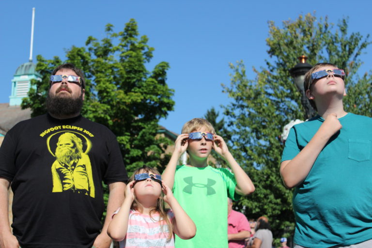 Kyle McRay, of Camas, and his children (from left to right) Grace, 7, Joseph, 11, and Levi, 13, watch the 2017 solar eclipse in front of the Camas Library on Monday morning, Aug. 21. Photo by Kelly Moyer/Post-Record