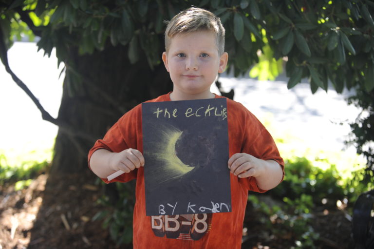Kaden Fenne, of Washougal, holds the art he made with pastels during the historic solar eclipse. Kaden and his family attended the eclipse-viewing party at the Camas Library on Monday morning, Aug. 21, along with several hundred others. Photo by Kelly Moyer/Post-Record