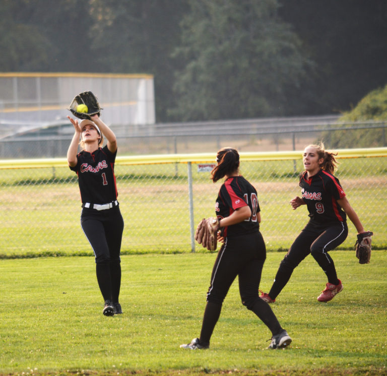 Camas High School senior Payton Bates catches a fly ball in left field for the Papermakers, while Sophie Franklin (right) and Taija Souki provide assistance. Defense has been key to Camas' 22-0 record this season.