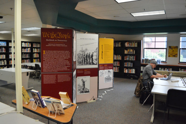 A Washougal High School student works in the library during lunch, while the &quot;Herblock on Democracy&quot; exhibit stands in the background. These historical political cartoons will be on display at the library through Friday, Nov. 17.