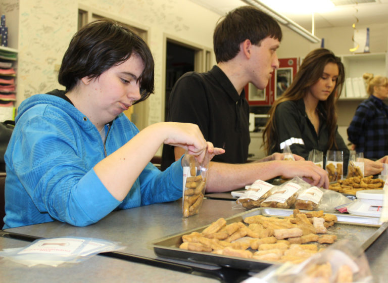 Transition House students Lindsey Meritt, 18, (left) and Gavin Johnson, 19, (center) work with Camas High senior Keelie LeBlanc (right) to package the &quot;Puppermakers&quot; dog treats they made as part of an ongoing fundraiser and job-skills project for the special needs students who attend the Camas School District&#039;s Transition House, for ages 18 to 21.
