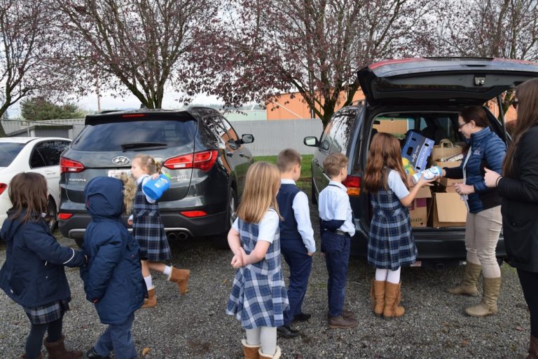 The students from Camas Christian Academy help Curriculum Director Ashley Schlauch unload her van full of donations for the WCGHS.