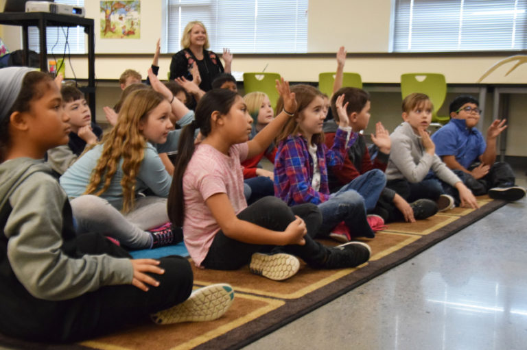 The students of Heidi Kleser&#039;s third grade class engage in the Wolfways presentation by focusing on the presenters and raising their hands to answer questions.