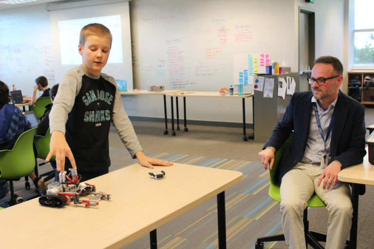 Beck Gummer, a seventh grader at Odyssey Middle School, explains to Principal Aaron Smith, his assignment to design a robot that would be able help army men rescue people during natural disasters on Monday, Dec. 4 .