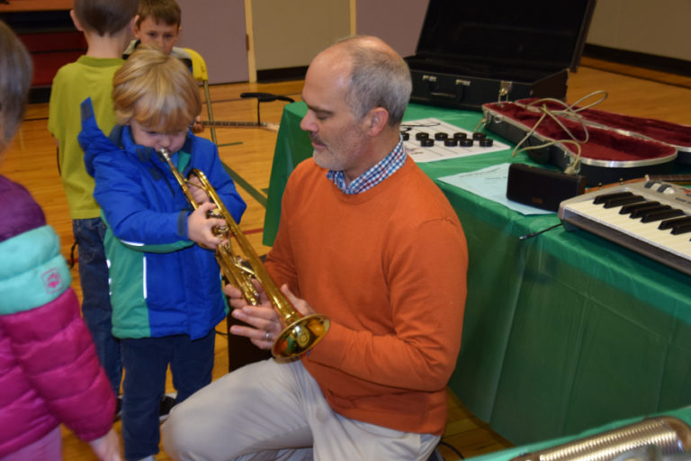Rob Melton, owner of Opus School of Music, aids Alexander Lampmann, a preschooler at Hathaway Elementary, as Lampmann plays the trumpet during the Dream Big event on Dec.