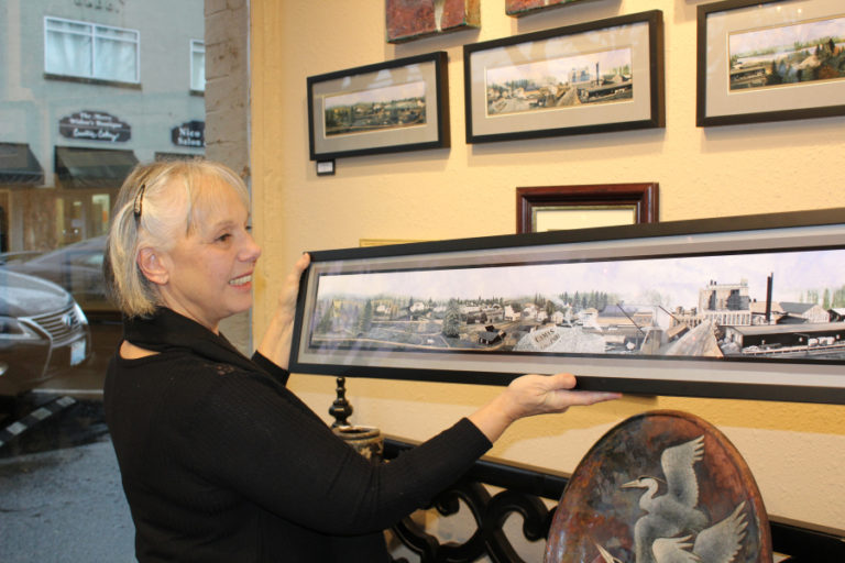 Maria Grazia Repetto holds a print of her mural featuring historic downtown Camas, circa 1900. The original mural hangs over the front entrance of the Camas Gallery, at 408 N.E. Fourth Ave., and prints, including the one shown here, are sold inside the gallery.