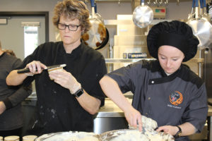 Culinary instructor Brenda Hitchins tops a tiramisu cup with a layer of cream filling while Washougal High School Sophomore Alexis Garrett refills an icing bag to continue making the dessert cups. Garrett says she likes the teamwork and hands-on learning that the culinary program offers.