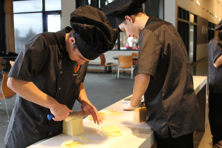 Washougal High School senior Nathan Beaver (left) and sophomore Mason Johnson (right) slice cheese for a chicken cordon bleu dish. Beaver says he is interested in the culinary program at Clark College, while Johnson wants to take business and marketing classes at Washington State University after high school.