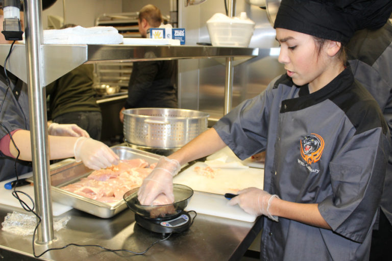 Washougal High student Andres Magana cuts and weighs chicken pieces to prepare chicken cordon bleu.