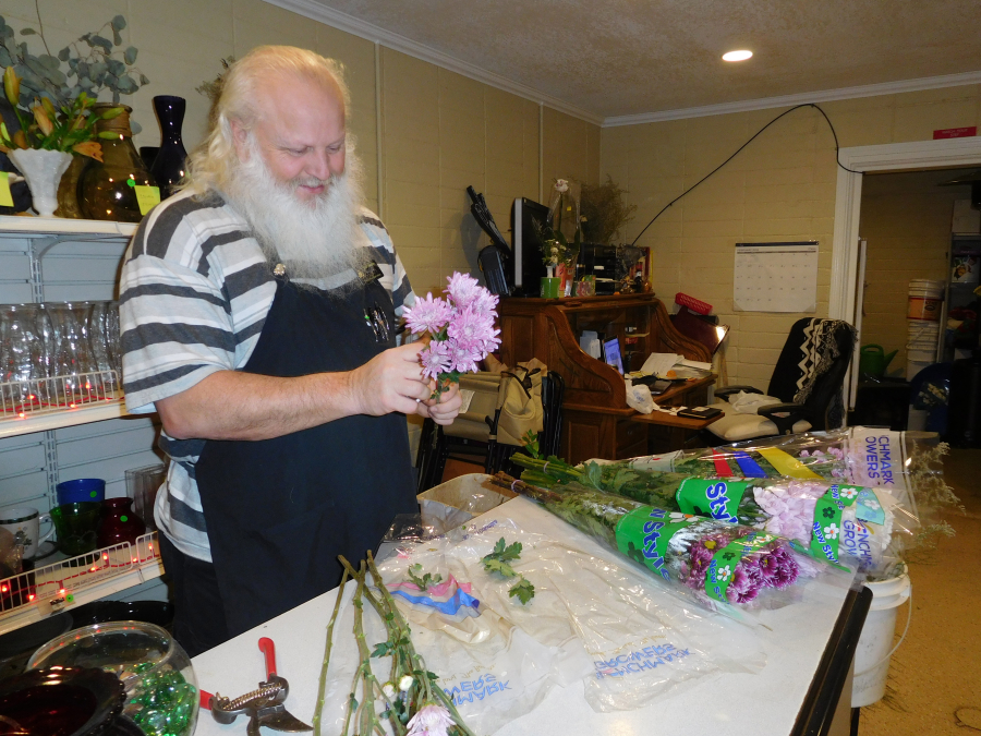 Tim Carroll, an employee at Mystic Gardens, in Camas, preps mums for display. He and Mystic Gardens owner Leslie Rick (not pictured), are both ordained to officiate at weddings. Mystic Gardens started offering drive-thru weddings in January. So far, there have been no takers.