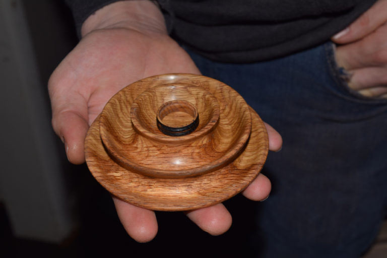 John Furniss holds a bowl and ring that he created through woodworking.