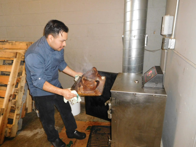 Alex Ramirez, co-owner of Alex Smokehouse, checks on turkey in a smoker at the downtown Washougal restaurant.