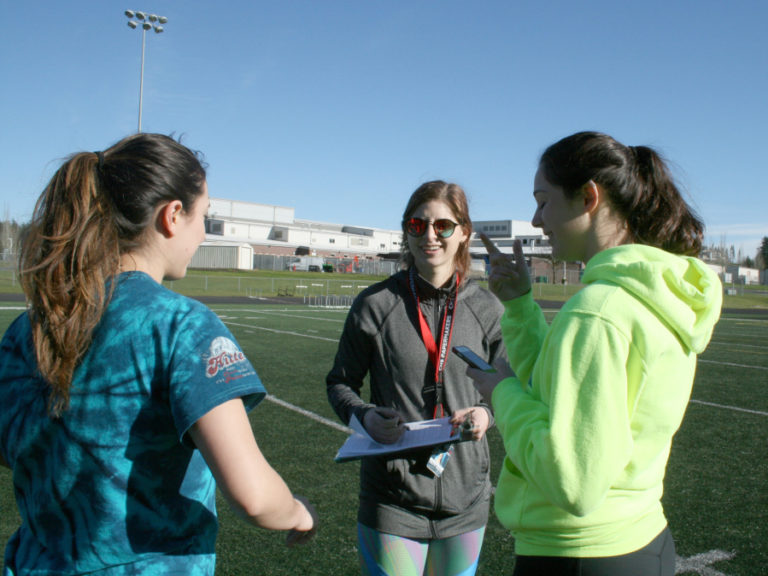 An athlete picks up some pointers from long jump coach Michelle Pillette (center) and new head track coach Seanna Pitassi (right) at Camas High School during one of the first practice sessions of the year.