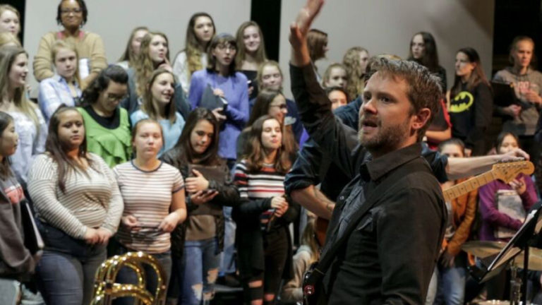 Composer Kelly Pratt directs 200 Camas High School choir students during rehearsal for the upcoming concert that will blend together the voices of the students with rock band Bright Moments.