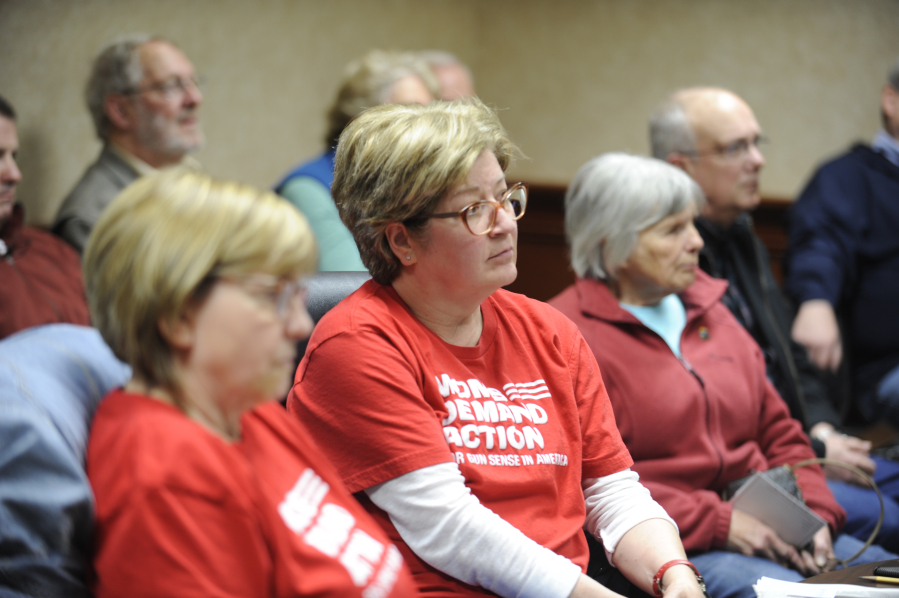 Wearing their signature, red "Moms Demand Action" T-shirts, Moms Demand Action for Gun Sense in America members Jane Miletich (left) and Shelia Pearce (center), along with several members of the Washougal City Council in the background, listen at a town hall hosted by Republican lawmakers Sen. Ann Rivers and Rep. Brandon Vick on Saturday, April 14, at Camas City Hall. (Kelly Moyer/Post-Record)