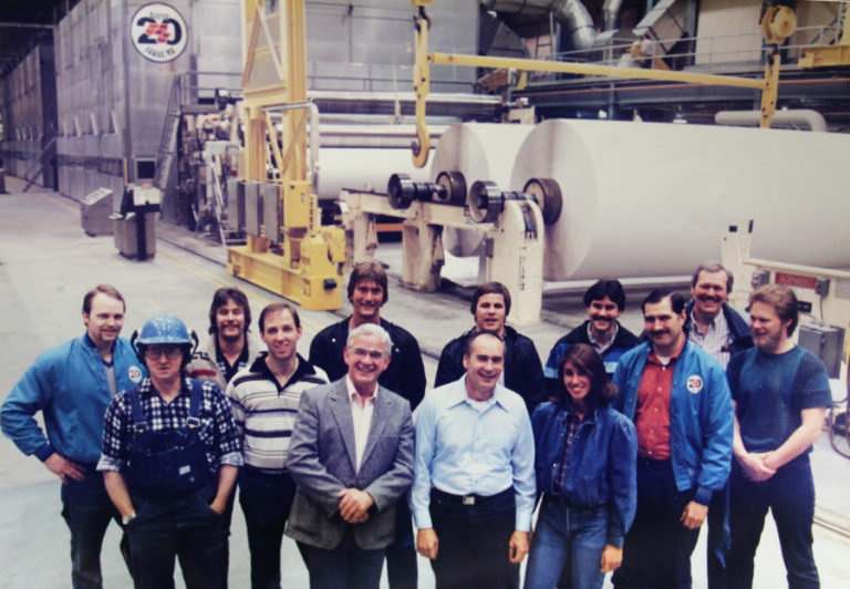 Jerry Nichols (blue shirt, front center), a retired Camas paper mill shift supervisor, stands with members of the original start up crew for the &quot;Roaring 20&quot; paper machine, shown in the background, in 1984.