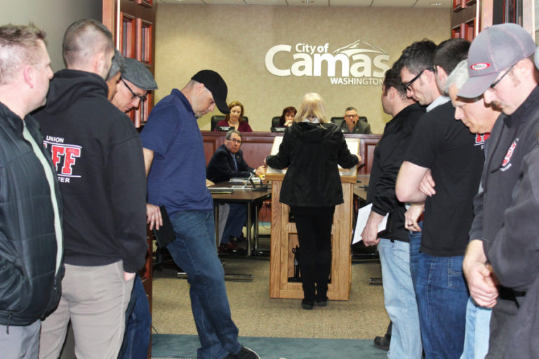 Firefighters bow their heads outside a March 19 Camas City Council meeting, while Cathy Nagode, of Camas, talks about the Feb. 14 fire that trapped her longtime boyfriend, Arthur Nichols, and the couple&#039;s dogs inside their home. Firefighters rescued Nichols and the dogs. Nichols died eight days later. Many have publicly claimed his death stemmed from smoke inhalation, but a death certificate says Nichols died from cancer and does not list the fire or smoke inhalation as a contributing factor.